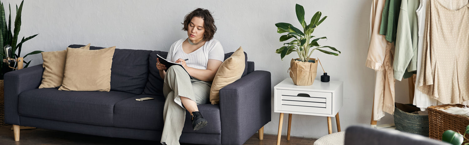 Woman sitting on a couch and writing in a journal